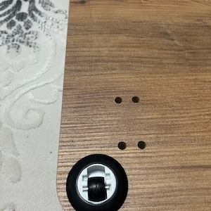 Puede incluir: Superficie de escritorio de madera con un patr&oacute;n de vetas de madera marr&oacute;n. El escritorio tiene dos ruedas negras con detalles blancos y cuatro agujeros peque&ntilde;os. El escritorio est&aacute; dise&ntilde;ado para la movilidad y la comodidad.