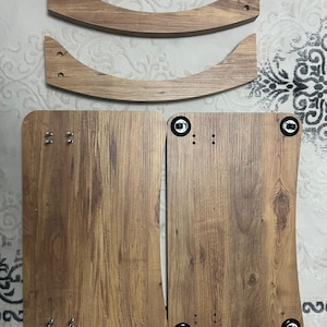 Puede incluir: Componentes de muebles de madera sin montar. La imagen muestra dos piezas de madera curvadas y dos piezas rectangulares con un acabado de vetas de madera. La ferreter&iacute;a, incluidos tornillos y pernos, es visible en las piezas. Los componentes parecen ser para una mesa o silla peque&ntilde;a.