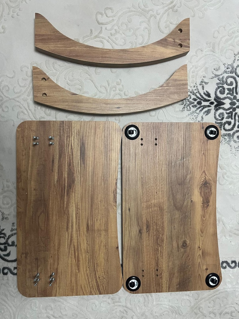 Puede incluir: Componentes de muebles de madera sin montar. La imagen muestra dos piezas de madera curvadas y dos piezas rectangulares con un acabado de vetas de madera. La ferreter&iacute;a, incluidos tornillos y pernos, es visible en las piezas. Los componentes parecen ser para una mesa o silla peque&ntilde;a.