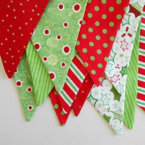 May include: A festive Christmas banner with alternating fabric triangles. Patterns include red with gold stars, green with white circles, red with green polka dots, and holly leaves. The banner is a holiday decoration.