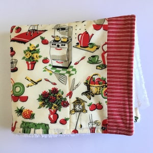 May include: A cream-colored kitchen towel with a red border and a white terry cloth backing. The towel features a vintage kitchen design with red, yellow, and green illustrations of kitchen appliances, food, and flowers.