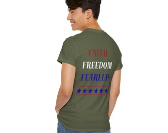 Puede incluir: Camiseta verde oliva con las palabras "FAITH FREEDOM FEARLESS" en rojo, blanco y azul, con una fila de estrellas azules debajo. La persona lleva vaqueros azules.