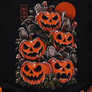 Puede incluir: Camiseta negra con un diseño de Halloween con calabazas naranjas, cuervos y una luna roja. El diseño incluye lápidas y texto japonés. La camiseta está rodeada de calabazas y decoración otoñal.