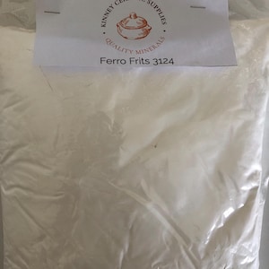 May include: A clear plastic bag filled with white powder. A white label at the top reads "Kinney Ceramic Supplies Quality Minerals" with a logo of a pot. Below the logo is the text "Ferro Frits 3124".