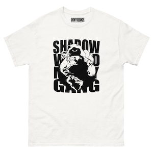 May include: White t-shirt with a black graphic of a figure on top of a globe, with the words "SHADOW WORLD GANG" in large, bold letters. The shirt also has the text "KNOWYOURANGEL" at the top.