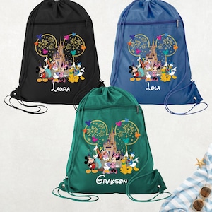 May include: Three drawstring backpacks in black, blue, and green. Each bag features a colorful graphic of Disney characters in front of a castle, with the text "Laura", "Lola", and "Grandson" below. The bags have a zippered front pocket.