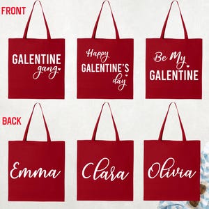 May include: Red tote bags with white text. The front of the bags say "GALENTINE gang", "Happy GALENTINE'S day", and "Be My GALENTINE". The back of the bags say "Emma", "Clara", and "Olivia".