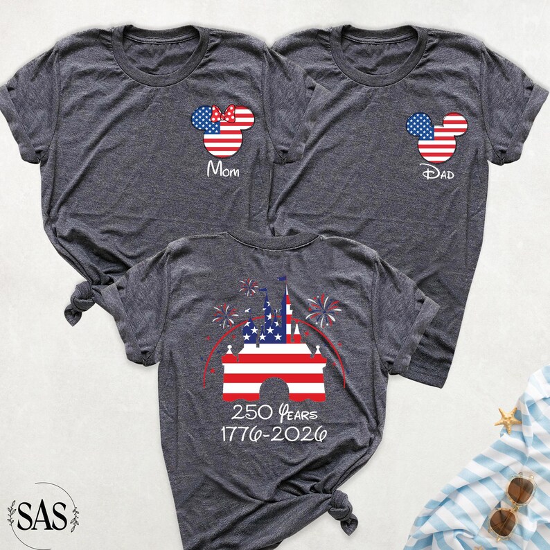 May include: Three dark gray t-shirts with patriotic Mickey Mouse designs. One shirt says "Mom" with a bow, another says "Dad", and the third features a castle graphic with "250 Years 1776-2026".