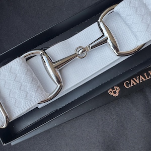 May include: A white elastic belt featuring a silver-toned metal horse bit buckle. The belt has a textured diamond pattern and is presented in a black box labeled with the text CAVALLA & CO. The design includes silver metal hardware loops.
