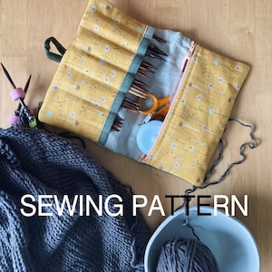 Può includere: Un astuccio per aghi in tessuto giallo con chiusura a zip e motivo floreale. L'astuccio è pieno di ferri da maglia e un paio di forbici. Il testo "SEWING PATTERN" è stampato sull'immagine.