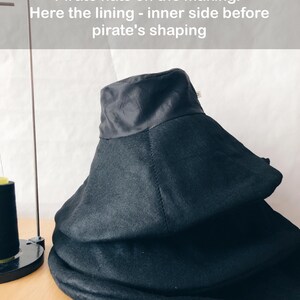 May include: Black pirate hats in various stages of construction. The hats are stacked, showing the lining and the shaping process. The text on the image reads: "Pirate hats on the making. Here the lining - inner side before pirate's shaping."
