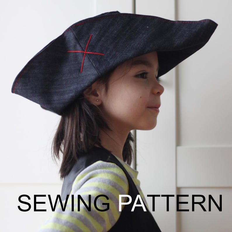 Pode incluir: Um chap&eacute;u de pirata azul escuro com uma cruz vermelha costurada na frente. O chap&eacute;u tem uma aba larga e costuras vermelhas nas bordas. O texto "SEWING PATTERN" &eacute; exibido em branco na parte inferior da imagem.