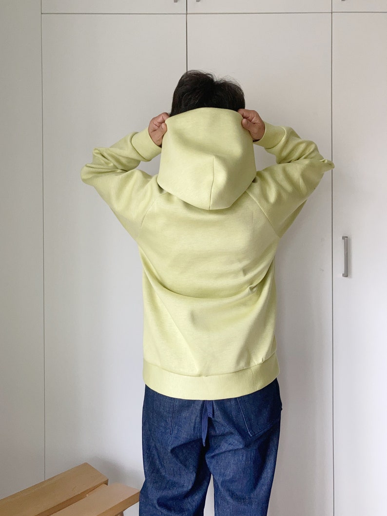 Woman wearing an oversize hoodie. Without logos. Color citric yellow. View from the back