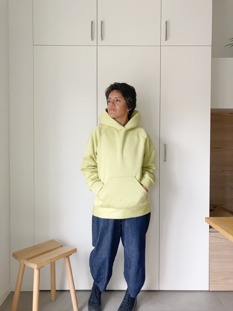 Short hair woman wearing an oversize hoodie. Without logos. Color citric yellow