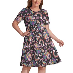 Peut inclure: Robe noire à manches courtes ornée d'un motif fantaisiste de champignons, d'arcs-en-ciel et de fleurs dans des tons de violet, vert et jaune. La robe a une encolure ronde et une jupe évasée, créant un look joyeux et coloré.