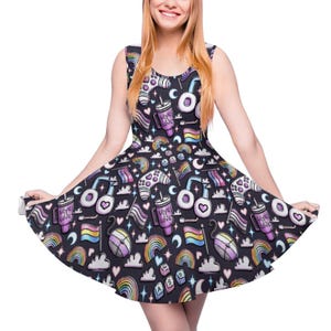 May include: Sleeveless skater dress with a black background and a repeating pattern of rainbows, hearts, game controllers, and coffee cups. The dress features a scoop neckline and a flared skirt, perfect for a casual, fun look.