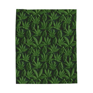 May include: A dark green blanket with a repeating pattern of green cannabis leaves and cone-shaped buds. The leaves and buds are raised, creating a textured surface. The blanket is rectangular.