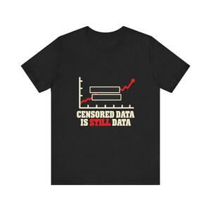 May include: A black short-sleeve t-shirt featuring a graphic of a red line graph with two black rectangular bars obscuring parts of the data. Below the graph, the text reads: CENSORED DATA IS STILL DATA, with the word STILL printed in red.
