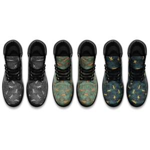 May include: Six pairs of combat boots with dragonfly patterns. The boots have black laces and soles, with uppers in shades of grey, teal, and blue. The dragonfly designs vary in colour, including white, gold, and orange.
