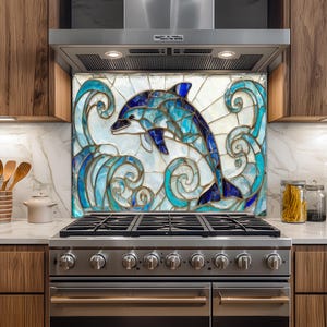 May include: A kitchen backsplash featuring a stained glass design of a dolphin leaping through ocean waves. The dolphin is depicted in shades of blue, with white and teal accents. The backsplash is installed above a stainless steel gas range.