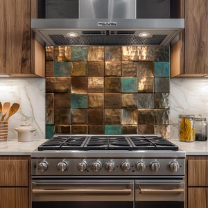 May include: A kitchen backsplash featuring square tiles in brown, copper, and teal hues. The tiles have a textured, hammered finish. The backsplash is positioned above a stainless steel gas hob and beneath a stainless steel extractor hood.