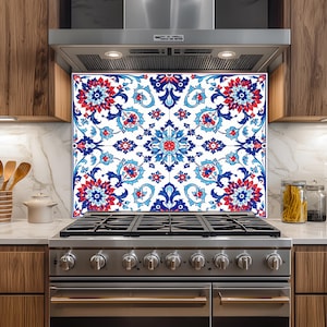 May include: A decorative kitchen backsplash with a floral pattern in red, blue, and white. The design features stylized flowers and leaves. The backsplash is installed above a stainless steel gas range in a modern kitchen.