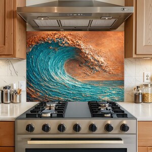 Op de afbeelding: Een keukenachterwand met een textuurschilderij van een grote oceaangolf. De golf is afgebeeld in tinten turquoise en blauw, met een kam van oranje en bruin. De achterwand is geïnstalleerd boven een roestvrijstalen fornuis.