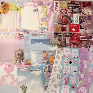 May include: A selection of stationery items, including notepads, stickers, and decorative papers. The items feature pastel colours, cute illustrations, and Japanese text. The assortment includes star-shaped notes, animal characters, and food-themed stickers.