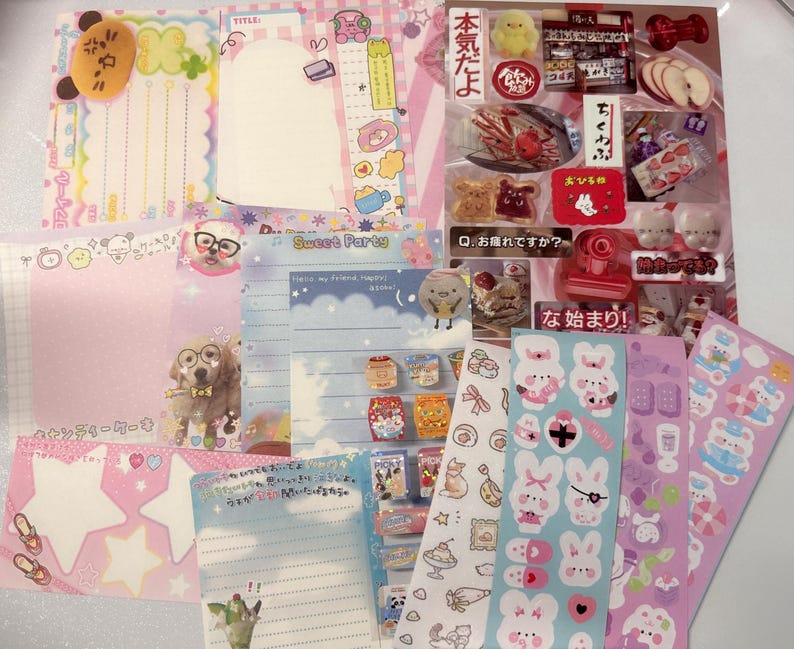 May include: A selection of stationery items, including notepads, stickers, and decorative papers. The items feature pastel colours, cute illustrations, and Japanese text. The assortment includes star-shaped notes, animal characters, and food-themed stickers.