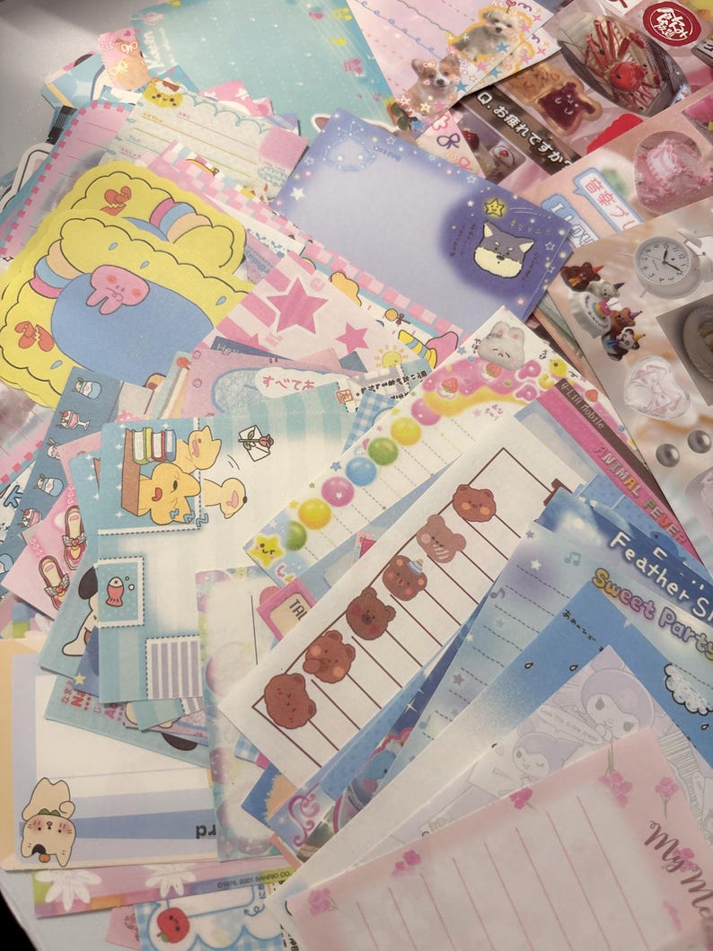 May include: A selection of colourful stationery, including notepads and stickers, with diverse designs. The designs feature cartoon animals, stars, and floral patterns. The colour palette includes pastel pinks, blues, and yellows.