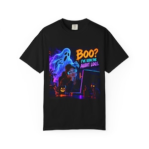 Può includere: Una t-shirt nera a maniche corte con la grafica di una persona al computer e un fantasma blu luminoso alle spalle. Il testo recita "BOO? I'VE SEEN THE AUDIT LOGS." Il design include una tazza a forma di zucca e luci al neon.