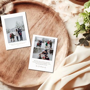 May include: Two white holiday cards with family photos on a wooden tray. One card has a single photo with text, the other has three photos and holiday greetings. The cards feature family portraits in a snowy outdoor setting.