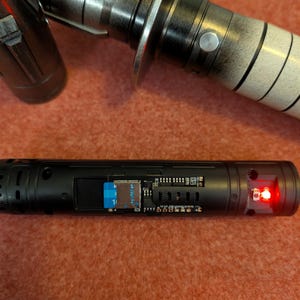 Puede incluir: Una empu&ntilde;adura de sable de luz negra y plateada con una luz roja en el extremo. La empu&ntilde;adura tiene un dise&ntilde;o detallado con un protector de hoja plateado. La secci&oacute;n inferior de la empu&ntilde;adura tiene una ranura para una tarjeta SD.