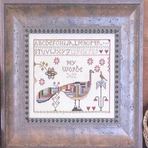 Può includere: Un ricamo a punto croce incorniciato che presenta un pavone colorato con il testo "My Worke 2022". La cornice è in legno rustico con una finitura invecchiata.