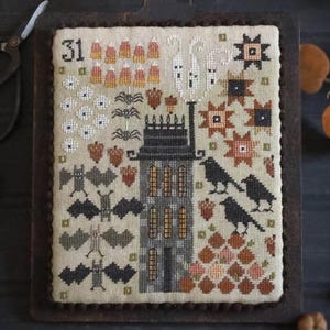 Puede incluir: Un muestrario de punto de cruz con temática de Halloween. El diseño presenta una casa embrujada, murciélagos, fantasmas y calabazas. El número "31" está en la parte superior izquierda. El muestrario está montado en una tabla de cortar de madera.