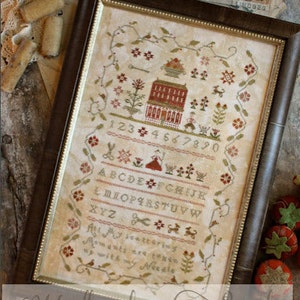 May include: A framed cross-stitch sampler with a house, flowers, and a garden scene. The sampler includes the alphabet, numbers, and the text "All My Scattering Moments are Woven Up with My Needle".