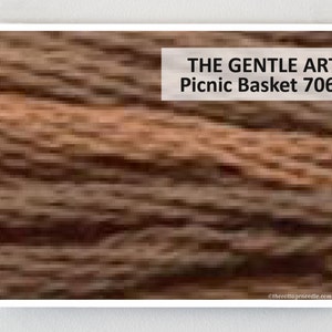 May include: A close-up of a brown and tan woven picnic basket. The text "THE GENTLE ART Picnic Basket 7060" is visible in the upper right corner of the image.