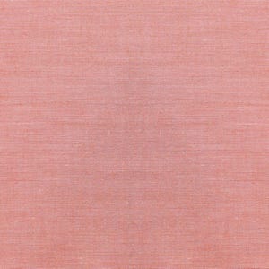 Op de afbeelding: Close-up van een getextureerde, koraalkleurige stof. Het materiaal heeft een subtiel, geweven patroon en een warme, gedempte roze-oranje tint. De stof lijkt effen van kleur te zijn met een licht ruwe textuur.