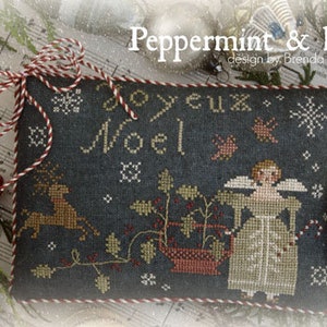 Könnte beinhalten: Ein Kreuzstich-Sampler mit dunkelblauem Hintergrund, der einen Weihnachtsengel, ein Rentier, Stechpalme und den Text "Joyeux Noel" zeigt.