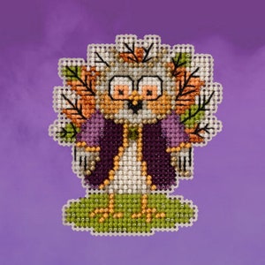May include: A cross-stitch pattern of a cartoon owl wearing a purple robe and a crown of leaves. The owl has large, round eyes and a small beak. The owl is standing on a green patch of ground.