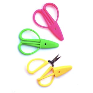 May include: Three pairs of colourful, small scissors with protective cases. The scissors are pink, green, and yellow.