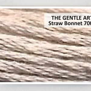 May include: A close-up of a woven straw bonnet, with a light brown color. The text "THE GENTLE ART Straw Bonnet 7002" is printed on a white rectangle in the upper right corner of the image.