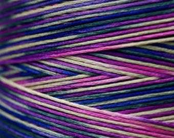 May include: A spool of multi-colored embroidery floss with shades of purple, pink, blue, and beige.