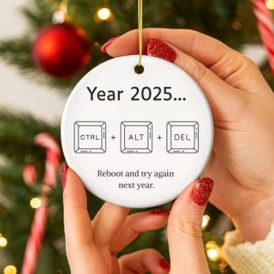 May include: A white ceramic Christmas ornament with the text "Year 2025..." and the keyboard shortcuts "CTRL + ALT + DEL". The ornament also includes the phrase "Reboot and try again next year."