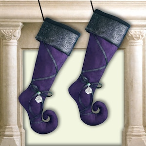 May include: Two purple velvet Christmas stockings with black ribbon and a silver rose charm. The stockings have a pointed toe and are decorated with black velvet trim.