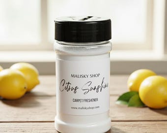 Może przedstawiać: Przezroczysty słoik odświeżacza do dywanów z czarną pokrywką, z etykietą "Citrus Sunshine" z Malisky Shop. Słoik stoi na drewnianej powierzchni z cytrynami i zielonymi liśćmi. Widoczna jest również strona internetowa www.maliskyshop.com.