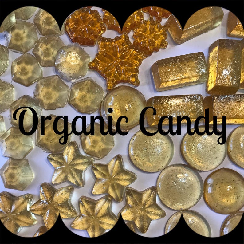 May include: A variety of organic candies in different shapes, including stars, snowflakes, and geometric shapes. The candies are all a translucent golden color and are arranged on a white surface. The text "Organic Candy" is written in black letters across the center of the image.