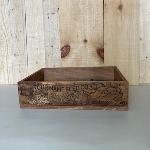 May include: A wooden box with a floral design and the text "YOUR NAME SEED CO. Est. Date Your Location".