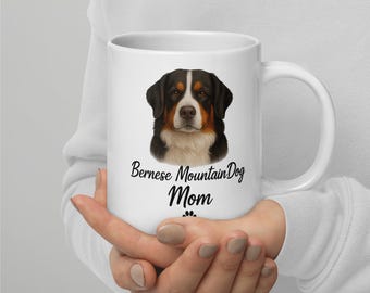 Peut inclure: Une tasse en céramique blanche avec une illustration détaillée du visage d'un Bouvier Bernois. La tasse porte l'inscription "Bernese Mountain Dog Mom" en écriture cursive. Le pelage du chien est noir, marron et blanc.