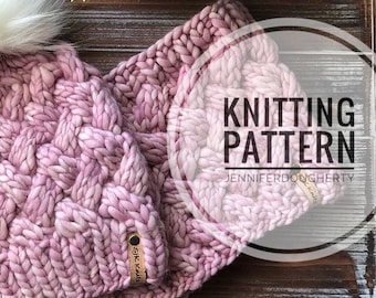 May include: A knitting pattern for a pink and white hat and scarf. The pattern is called "Knitting Pattern" and is by Jennifer Dougherty.